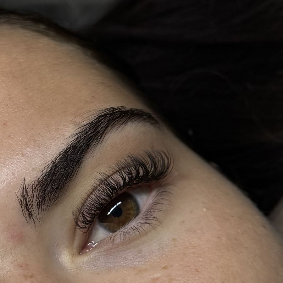 A Russian volume lash set, close-up of a hazel eye with full, fanned lashes beneath a groomed brow.